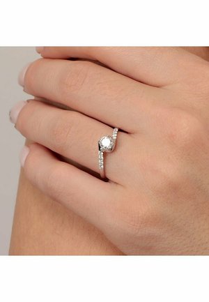 Silberner Ring mit einem zentralen runden Stein, umgeben von kleineren Steinen an einer Seite. Elegantes Band mit glänzender Oberfläche.