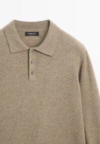 Beżowa wełniana koszulka polo, z klasycznym kołnierzykiem, zapięciem na trzy guziki i subtelną fakturą. Metka z napisem "Massimo Dutti."