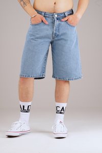 Light blue denim shorts, relaxed fit, knee-length with five pockets. Paired with white sneakers and crew-length socks featuring bold black text.