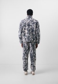 Fuzzy, oversized jacket and pants set in a black-and-white abstract pattern. Soft texture with elastic cuffs and pockets. Heavyweight material.