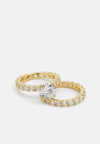 Anillos de oro con una gran piedra clara central y piedras redondas más pequeñas a lo largo de la banda, mostrando un acabado pulido y formas redondas.