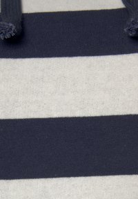 Navy ja kerma raidallinen kangas, jossa on pehmeä tekstuuri. Raidat ovat tasaisesti välimatkoilla, ja pinta on sileä neulottu. Kankaan yläosasta ulottuu kaksi langanpätkää.