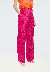 Roze wijde benen broek met een luipaardprint, gemaakt van een lichte stof met een gladde textuur en twee zijzakken.
