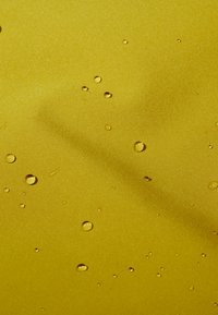 Żółty, gładki materiał z kroplami wody na powierzchni. Tekstura wydaje się lekko błyszcząca, odbijając światło wokół kropli.