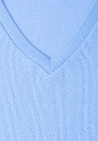 Gros plan d'un pull en maille bleu clair à col en V montrant un col côtelé et une texture fine en maille.