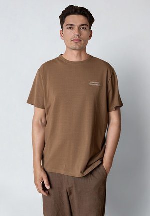 Brązowy t-shirt z krótkim rękawem wykonany z miękkiej tkaniny, z okrągłym dekoltem i subtelną nadrukowaną etykietą "CLEAN CUT COPENHAGEN".