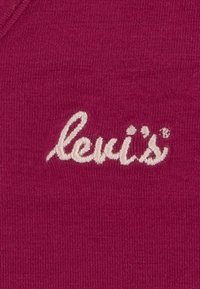 Tessuto bordeaux che mostra una sottile texture rigata con il logo bianco "levi's" ricamato in evidenza.