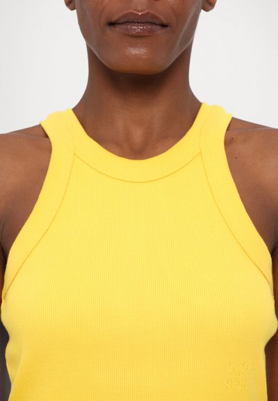 Geel geribbelde tanktop met een hoge halslijn en dikke banden, voorzien van een klein geborduurd logo aan de voorkant. Glad textuur.