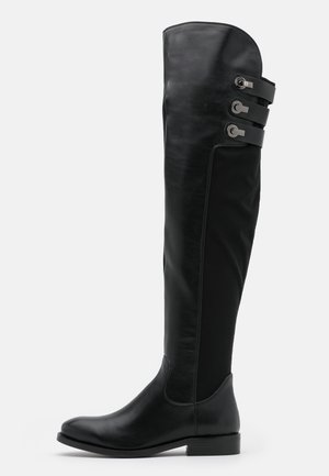 Botte en cuir noire montant jusqu'au genou avec talon bas et trois brides à boucle sur le côté près du haut.