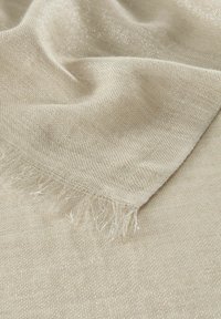 Tissu tissé beige avec un léger éclat métallique. Présente des bords frangés et une surface douce et texturée.