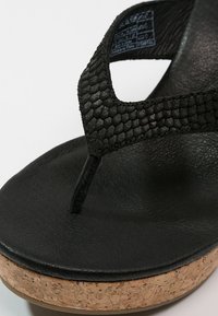 Černé žabky s texturovaným umělým koženým svrškem, korkovou mezipodešví a hladkou černou podešví. Disponují designem s thong páskem.