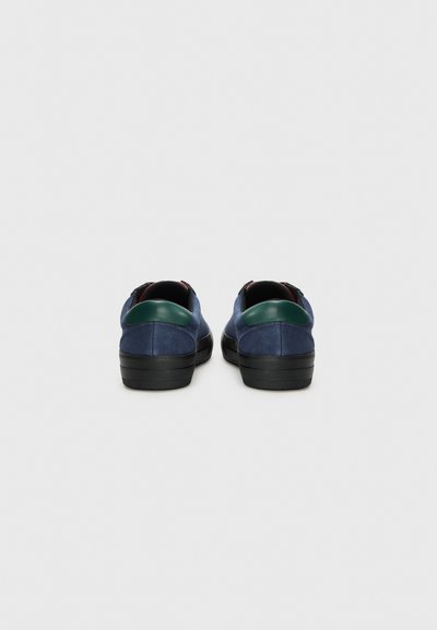 Tenisi din piele întoarsă albastră, cu talpă din cauciuc negru și accent verde la toc. Design de tip low-top, cu o textură netedă și formă rotunjită.
