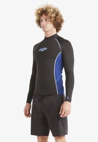 Black neoprene wetsuit top with blue accents, long sleeves, and a high neck. Paired with black board shorts. Features stitching details.