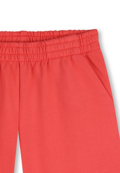 Koraalkleurige joggingbroek met een elastische tailleband, voorzien van twee zijzakken en een zachte, gestructureerde stof. Het ontwerp heeft een losse pasvorm.