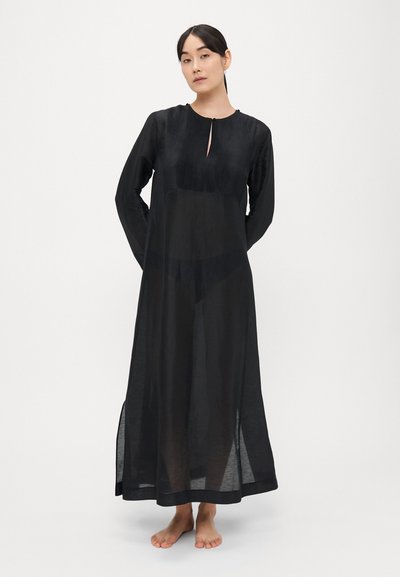 Rochie lungă neagră dintr-un material ușor, transparent, cu bodice plisat, mâneci lungi și un decolteu modest cu deschideri laterale.