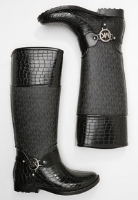 Bottes de pluie en caoutchouc noir avec une texture en relief évoquant celle des crocodiles, présentant une bande noire lisse et un accent logo en métal sur le côté latéral.