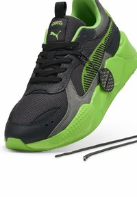 Svart och grå sneaker med gröna accenter, nät- och syntetiska material, texturerade sidor, rund tå och platta snören. Har en etikett.