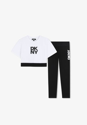 Witte crop top met zwart DKNY-logo en zwarte bies; gecombineerd met zwarte leggings met een wit DKNY-logo aan de zijkant.