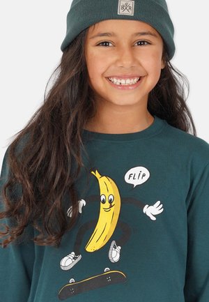 Langärmliges türkisfarbenes Hemd mit einer Grafik einer Banane mit Armen und Beinen, die Skateboard fährt, begleitet von dem Wort "FLIP" in einer Sprechblase.
