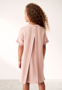 Rausva trumpomis rankovėmis suknelė iš minkštos medžiagos, su nugaroje centruota skyle ir apvalia iškirpte. Lygi tekstūra su susukti rankogaliais.