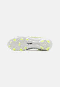 Nike sportsko med sål, der har en primært hvid base med grå detaljer, cirkulære gule grebsdutter og et sort logo.