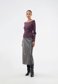 Long-sleeve purple top paired with a shiny silver midi skirt, complemented by black knee-high boots and a black bangle accessory.