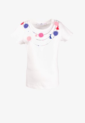Camiseta blanca de algodón con mangas cortas, con apliques de flores de fieltro coloridas y borlas a lo largo del escote, y cuentas decorativas.