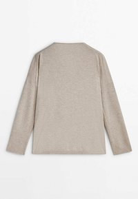 Chemise à manches longues beige clair, avec un col rond, une coupe décontractée et une texture douce, dotée d'entailles sur les côtés à l'ourlet pour faciliter le mouvement.