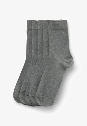 Cinq paires de chaussettes grises unies de longueur moyenne empilées soigneusement sur un fond blanc.