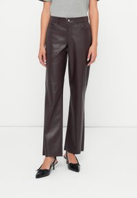 Barna műbőr nadrág, krokodilbőr mintával. Magas derék, egyenes szár, és két elülső zseb jellemzi.