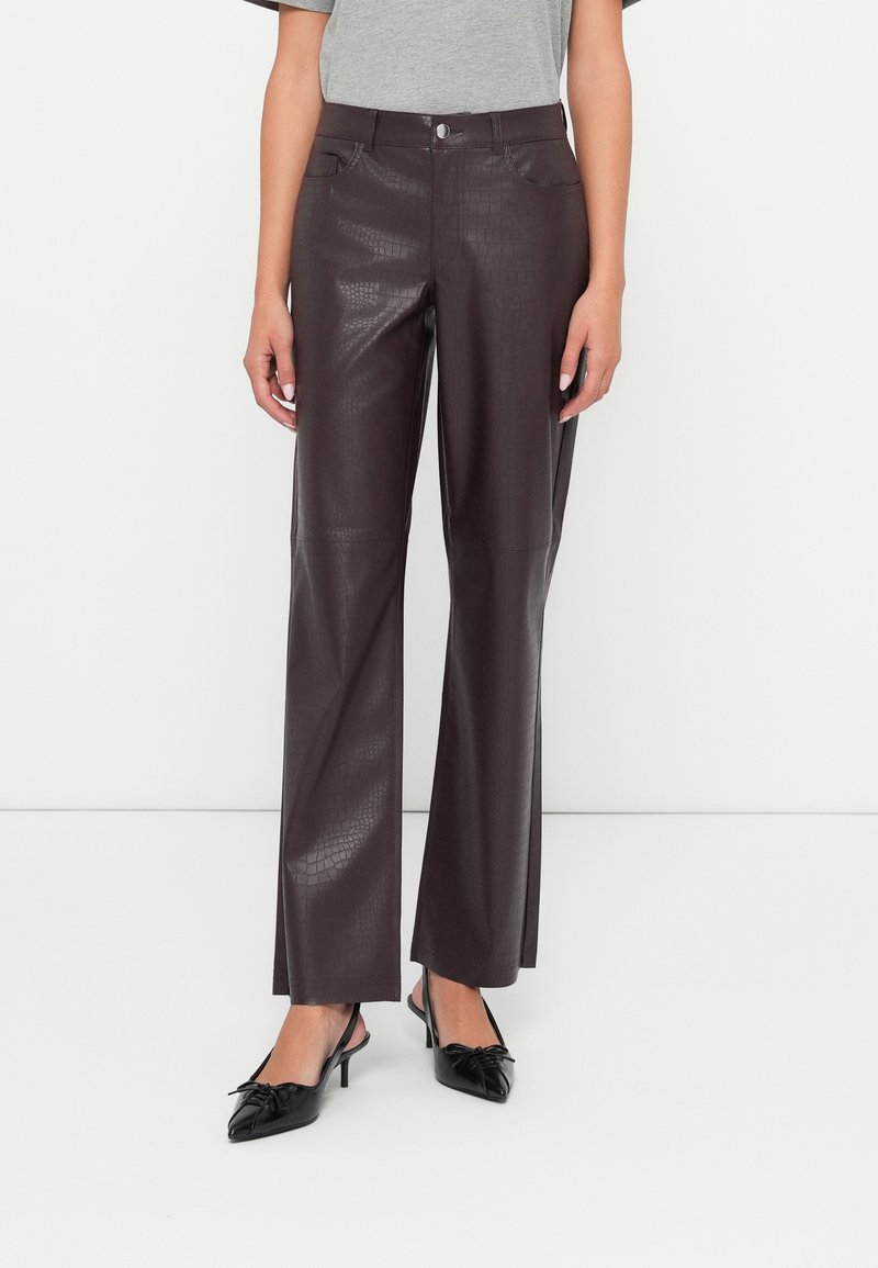 Barna műbőr nadrág, krokodilbőr mintával. Magas derék, egyenes szár, és két elülső zseb jellemzi.