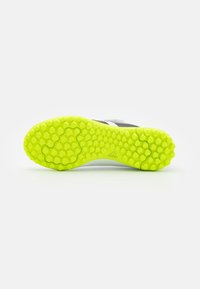 Sole of a neon yellow cleat with hexagonal grip patterns and adidas logo on a white background.