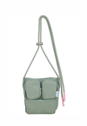 Small green fabric crossbody bag with three zippered pockets and adjustable cord strap featuring pink end caps.