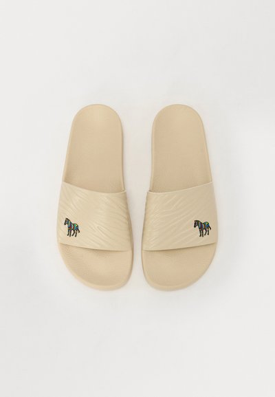 Beige slidesandaler med teksturerede stropper, der har et farverigt stribet zebra grafik på hver strop. Lavet af syntetisk materiale.