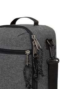 Borsa in tessuto grigio con un design squadrato. Presenta doppie cerniere, dettagli neri, una maniglia robusta e una superficie testurizzata per la durata.