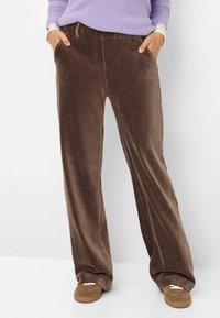 Bruine corduroy wijde benen broek met een zachte textuur, voorzien van zijzakken en een relaxte pasvorm, gecombineerd met tan kleurige schoenen.