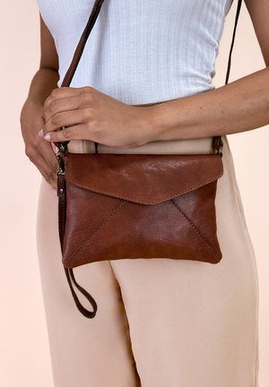 Braune Leder-Crossbody-Tasche in Form eines Umschlags, mit einer strukturierten Oberfläche und einem abnehmbaren Trageriemen. Nähte und Akzente sind sichtbar.