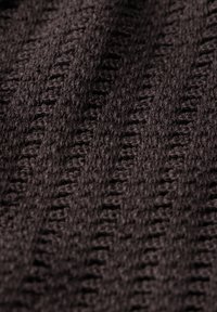Mørkebrun strikket stof med et struktureret, ribbet mønster og bløde, fuzzy fibre, der viser dybde og dimension.
