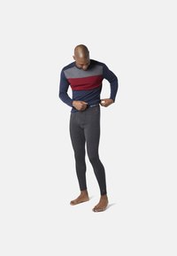 Herraktivitetskläder: långärmad marinblå skjorta med röda och grå ränder, ihop med mörkgrå leggings. Båda gjorda av elastiskt material.