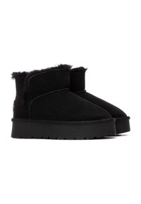 Botines negros de ante, con un forro suave y acolchado, punta redondeada y una suela de goma negra texturizada con un dibujo visible.