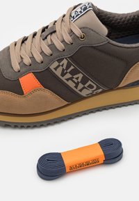 La sneaker presenta una toma in tela grigia con dettagli in suede marrone e un particolare arancione. Include una suola in gomma marrone e lacci blu.