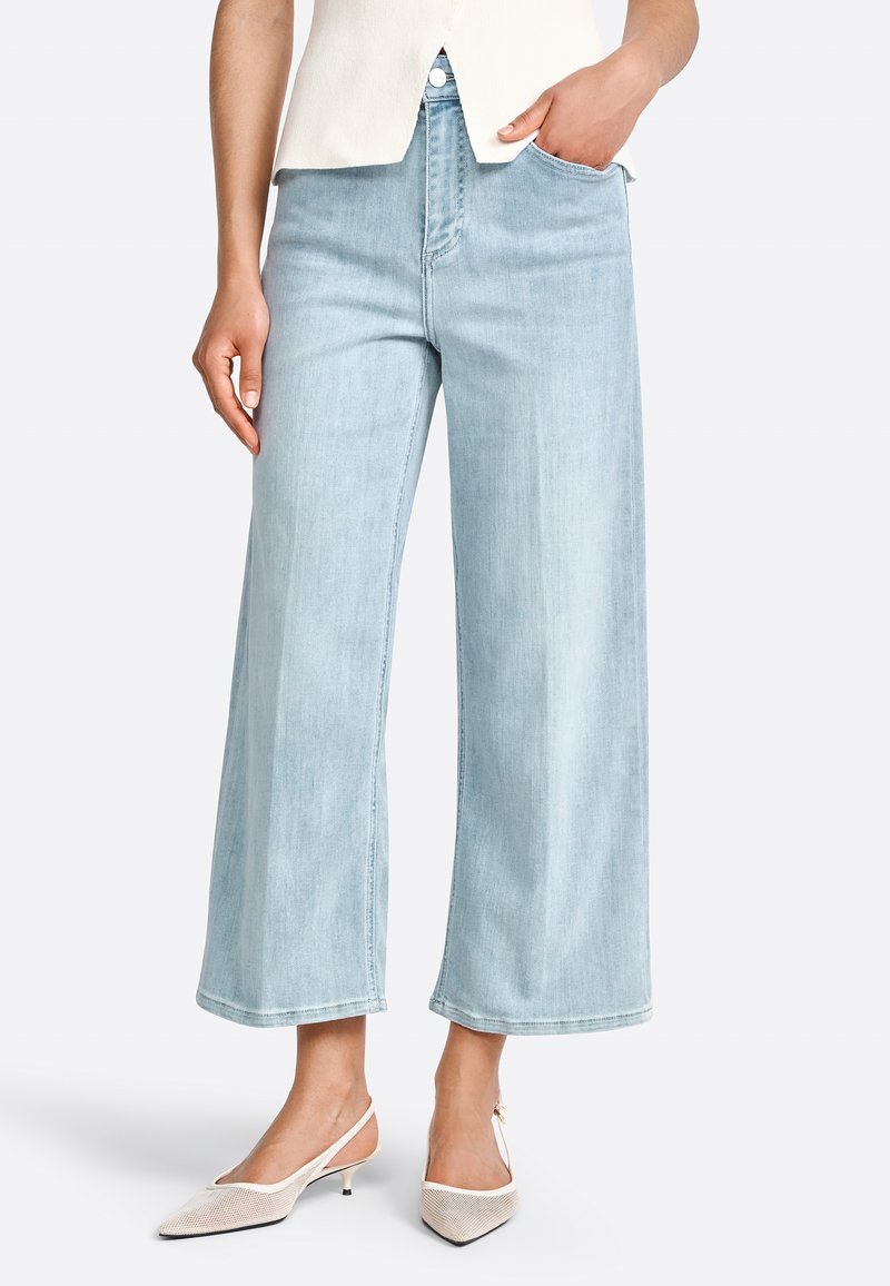 Jeans de mezclilla de corte ancho en azul claro, con una cintura alta, estilo de cinco bolsillos y un ligero desgastado.