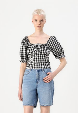 Blusa a maniche puff a scacchi bianco e nero con scollatura quadrata, abbinata a shorts di jeans blu chiaro. Tessuto strutturato, vita elastica.