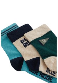 Tre par sokker: turkise med marineblå striber, beige med teksten "BLUE RIDGE" og grøn med en trekantaccent. Ribbet tekstur, længde til anklerne.