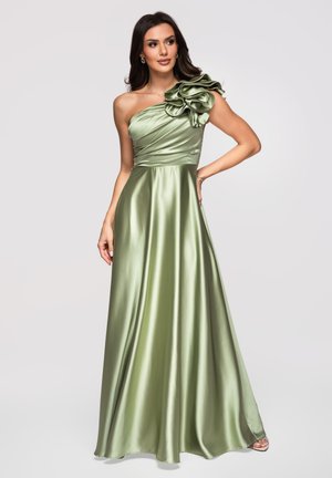Femme portant une robe en satin longue jusqu'au sol, asymétrique, vert clair avec un grand volant floral sur l'épaule.