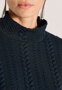 Marineblauer Rollkragenpullover mit strukturierten Zopfmustern. Aus einem dick gestrickten Stoff gefertigt, mit einem gemütlichen, strukturierten Kragen.