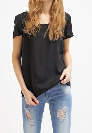 Top nero a maniche corte realizzato in tessuto liscio, con scollatura quadrata e vestibilità comoda, abbinato a jeans chiari strappati.
