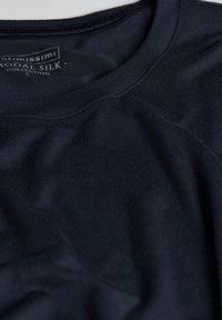 Ciemnoniebieska koszulka t-shirt z modalnego jedwabiu o gładkiej fakturze, okrągłym dekolcie i subtelnym połysku; metka widoczna w pobliżu kołnierza.