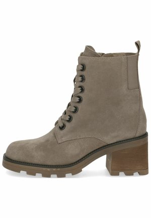 Bottine en daim beige avec un bout arrondi, un laçage à l'avant, un talon chunky et une semelle robuste. Elle présente des œillets noirs et une languette à l'arrière.