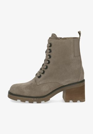 Tan suede ankle boot with a rounded toe, lace-up front, chunky heel, and rugged sole. Features black eyelets and a pull-tab at the back.